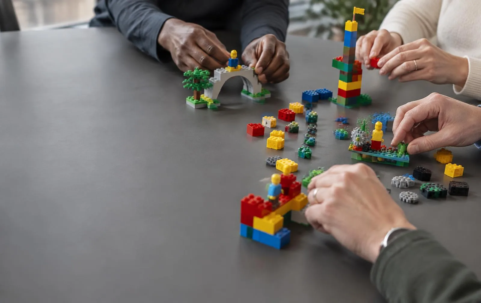 Illustrative workshop scene of adults building ideas with colorful LEGO bricks
